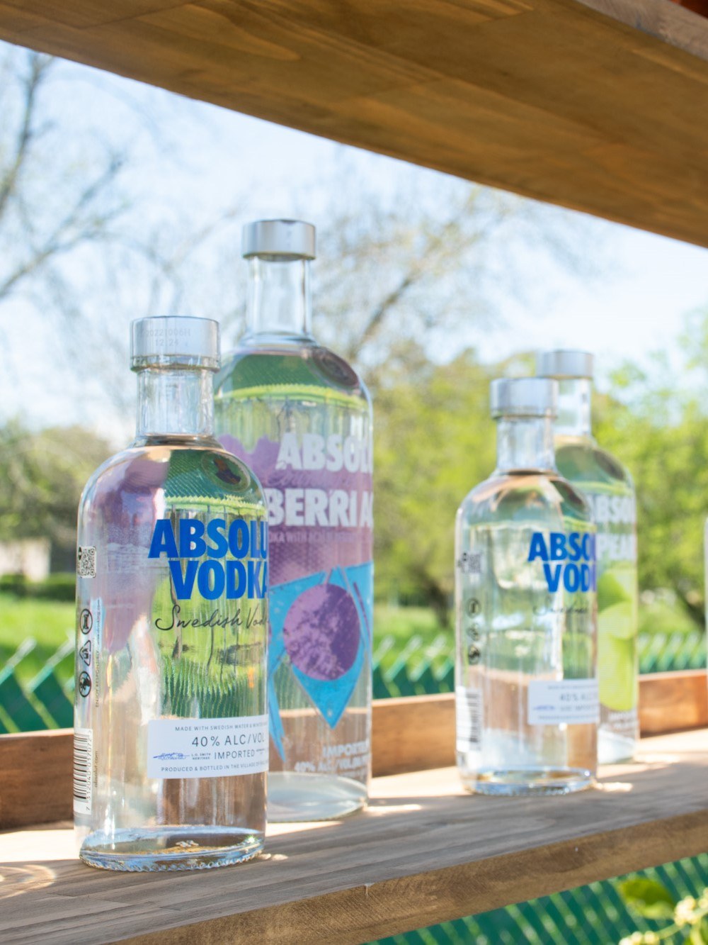 Botellas en una barra de madera con el jardín de fondo